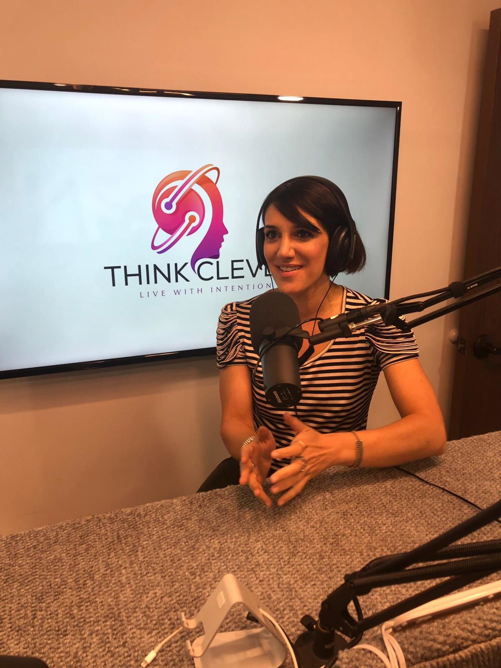 Sura speaking into a microphone as a guest on the Think Clever podcast