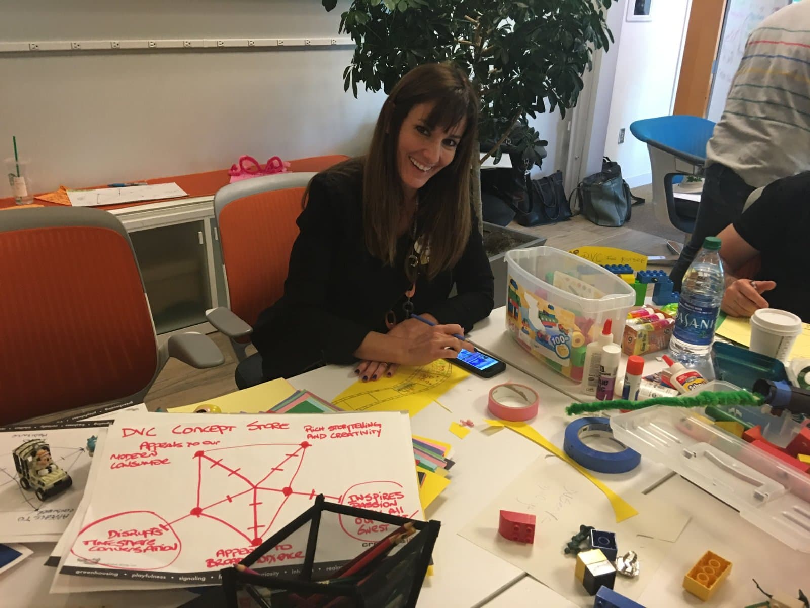 Sura sketching a concept map at a table full of prototyping materials