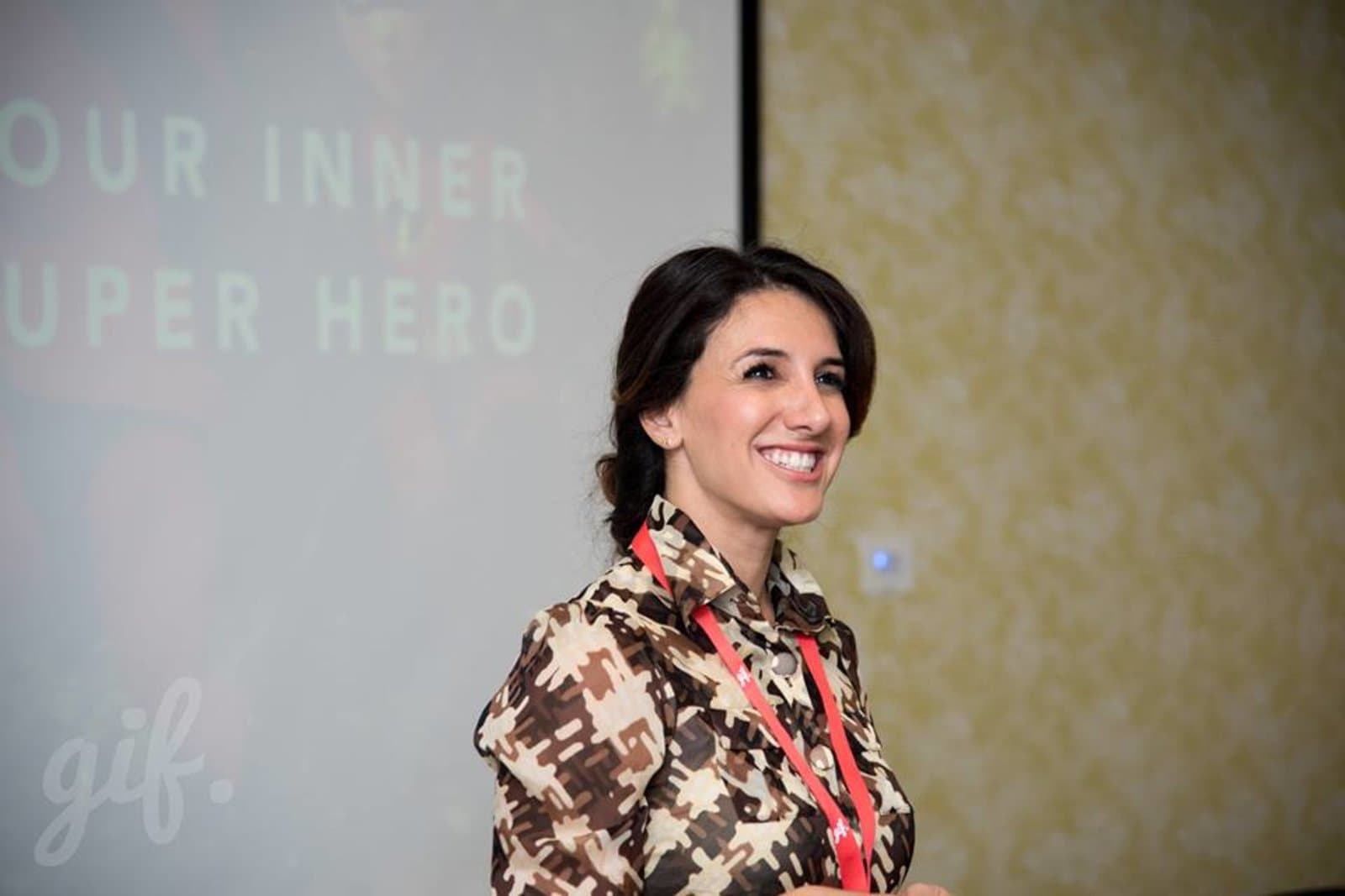 Sura smiling on stage in front of a slide that reads “Your inner super hero”